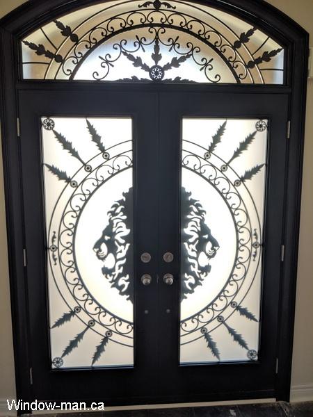 Double entry insulated front exterior doors. Black. Forest King Lions iron glass design. Matching round top arch head transom. Pic 1085 inside view